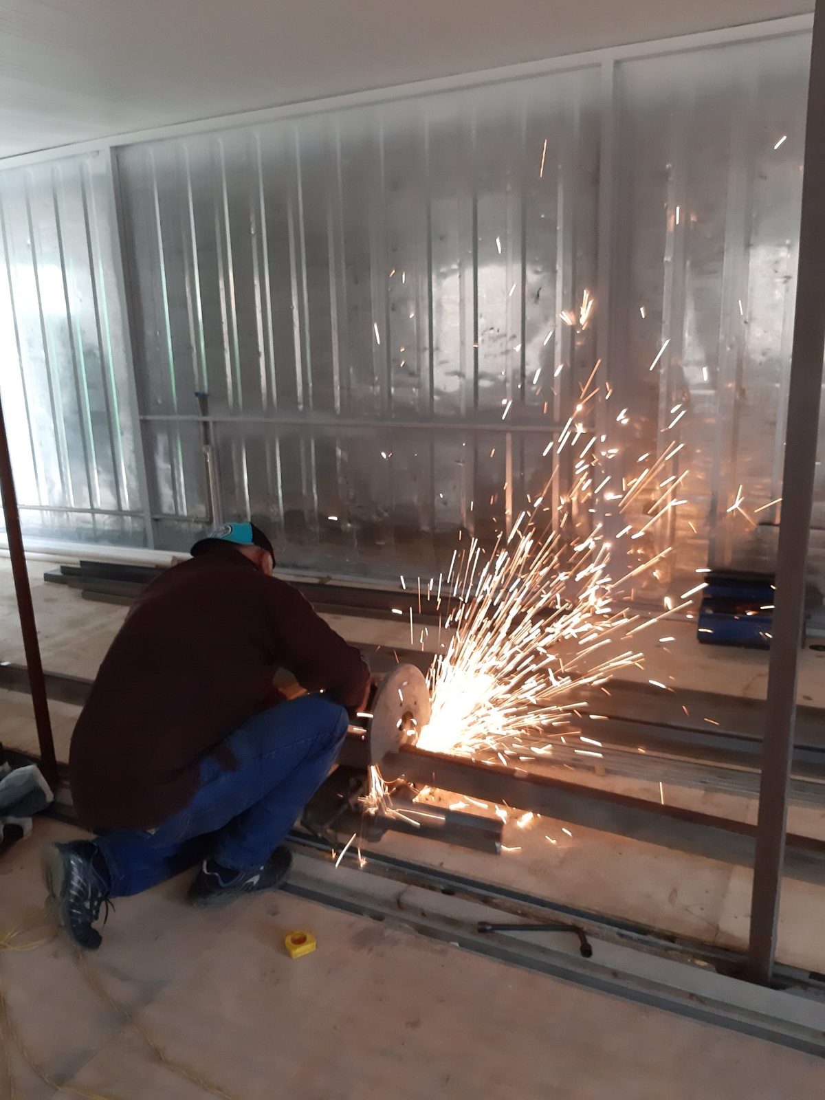 Worker cutting steel framing inside a container, sparks flying