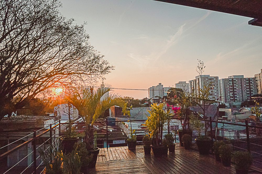 Rooftop com jardim da Teu Living ao pôr do sol, com vista de São Paulo