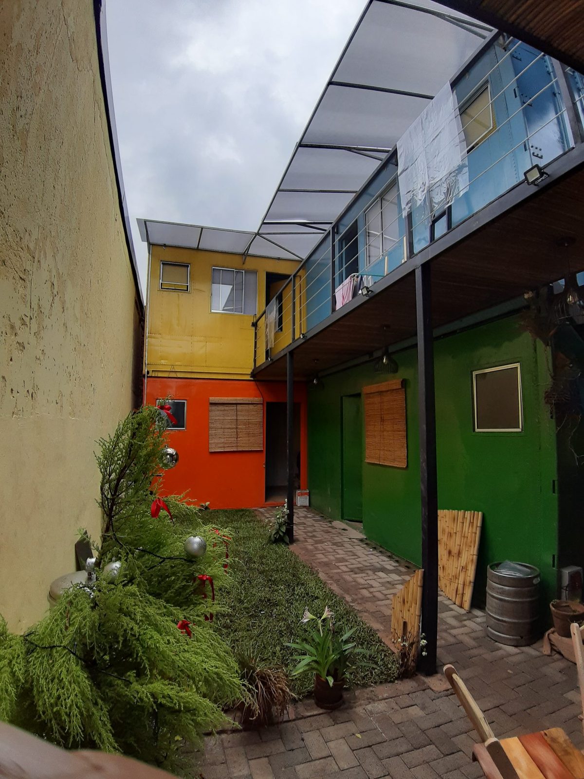 Pátio colorido entre os containers, com jardim, na Teu Living