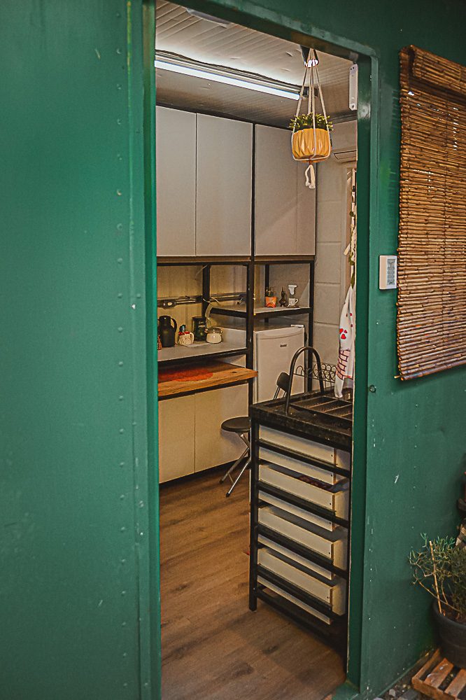 Porta verde do container abrindo para a cozinha aconchegante do Loft Ninho