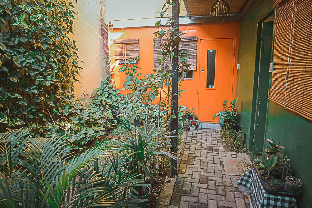Porta laranja do container e caminho de jardim no Loft Viajante