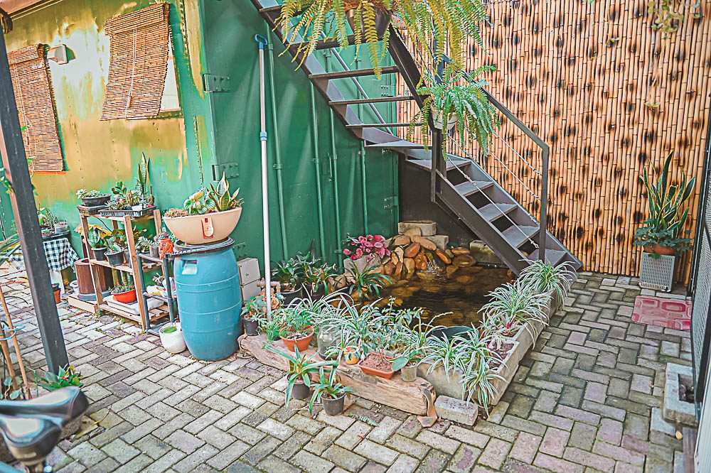 Container de aço verde renascido como lar, com jardim e fonte de água